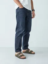 Pantalón jeans de corte slim y tiro medio, color azul oscuro, con diseño clásico de cinco bolsillos y trabillas para cinturón.
