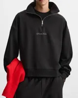 Buzo negro de cuello alto con cierre metálico y logo bordado en el pecho.