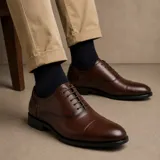 Zapato tipo Oxford de ecocuero color marrón, con diseño liso y suela de goma antideslizante.
