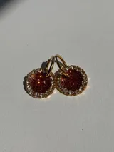 Aros de argolla dorados con dije circular de resina color cobre con glitter, rodeado de strass.