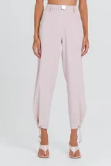 Pantalón estilo jogger de corte relajado y tiro alto, confeccionado en tela fluida color rosa pálido. Presenta cintura estructurada con hebilla metálica, pinzas frontales y ajuste con cordones en los tobillos.