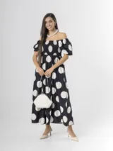 Vestido midi de color negro con estampado de lunares blancos, escote off-shoulder con elástico fruncido en el pecho y mangas cortas abullonadas.