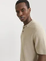 Polo de manga corta confeccionado en tejido de punto estructurado con textura sutil. Presenta cuello polo clásico, cierre frontal con botones y un corte regular.