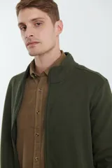 Cardigan de tejido de punto color verde militar, con cierre frontal de metal y cuello redondo. Presenta detalle de tejido plano en la cartera del cierre y en los bolsillos laterales.