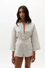 Short de lino color natural, de cintura alta con elástico en la parte trasera, ruedo curvo, bolsillos laterales y cierre frontal escondido.