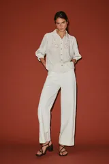 Camisa blanca a rayas sutiles, de cuello solapa y manga abullonada por debajo del codo. Presenta delicados bordados florales perforados en el frente y cierre frontal con botones.