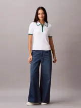 Chomba Calvin Klein de algodón con textura de punto fino, color blanco, con cuello polo y puños en contraste color verde. Presenta media cremallera frontal y diseño de manga corta.