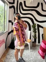 Camisa de manga corta con cuello, diseño estampado abstracto y geométrico en tonos rosados, marrones, amarillos y verdes. Cierre frontal.