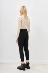 Pantalón tipo babucha de gabardina elastizada, color negro, con cintura elástica ajustable mediante cordón, puños en los tobillos, bolsillos diagonales frontales y bolsillos traseros con solapa y botón.