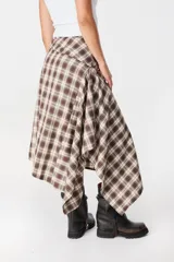 Falda midi de corte asimétrico con diseño de cuadros en tonos marrones y beige. Presenta una estructura rectangular que genera un drapeado natural al caer, con un estilo fluido y moderno.