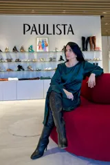 Vestido corto de satén color verde esmeralda, con mangas largas abullonadas, cuello redondo y diseño con drapeado lateral que genera un efecto asimétrico en el ruedo.