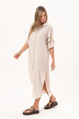Vestido camisero largo de lino color beige, con silueta relajada, abotonado al frente, cuello camisero, mangas regulables y tajos laterales.