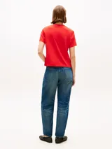 Remera Tommy Hilfiger de manga corta y cuello redondo, color rojo. Presenta un diseño gráfico bordado en el pecho con el nombre de la marca y texto descriptivo, además de la clásica bandera bordada en la manga.