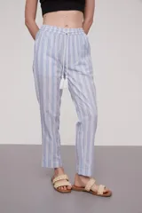 Pantalón babucha celeste con rayas verticales blancas, cintura elástica con cordón y detalle de borlas.