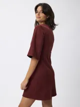 Vestido corto de gamuza sintética color bordó, con escote en V, mangas tres cuartos acampanadas y corte entallado en la cintura.