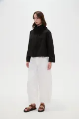 Campera corta de nylon en color negro, con cuello alto, capucha integrada y cierre frontal oculto con solapa.