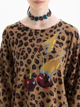 Sweater de punto con diseño animal print, cuello redondo y mangas largas con puños en contraste. Presenta un estampado central de cerezas y detalles bordados.