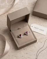 Aros tipo caravana de plata con diseño triangular y piedra central de circonia en forma de corazón color granate, rodeada por pequeñas circonias blancas.