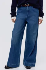 Pantalón de jean de tiro alto con corte wide leg y piernas amplias. Presenta diseño con raya frontal marcada, cierre con botón oculto, bolsillos laterales al bies y bolsillos traseros decorativos.