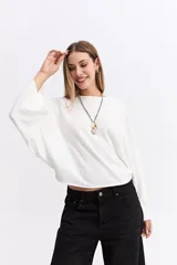 Blusa de corte relajado y fit holgado, con mangas largas amplias y textura sutil. Presenta un diseño minimalista con caída suave.