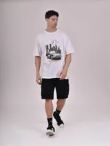 Remera negra de corte holgado con cuello redondo y manga corta. Presenta un pequeño estampado rectangular en el pecho con texto en blanco y líneas decorativas en rosado.