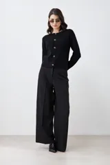Chaqueta tejida negra con botones dorados, de corte clásico y mangas largas.