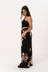 Pantalón palazzo negro con estampado floral en tonos rosa, naranja y amarillo. Tiene cintura alta con elástico.