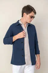 Sobre camisa color verde militar de lino con cuello clásico, manga larga con puños abotonados, cierre frontal con botones a tono y bolsillos de parche en el pecho.