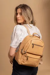 Mochila de cuero sintético color tostado, con compartimento principal amplio, bolsillo frontal con cierre y correas ajustables. Presenta un diseño práctico y ligero con asa superior.