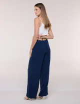 Pantalón wide leg blanco con finas rayas verticales oscuras, tiro alto, bolsillos laterales y pinzas frontales. Incluye un cinturón trenzado de rafia con hebilla rectangular.