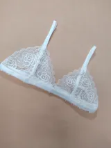 Bralette de encaje blanco con diseño de rosas, copas triangulares y tirantes finos ajustables.