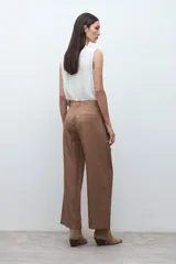 Pantalón de corte sastrero y pierna ancha, confeccionado en lyocell. Presenta pinzas en la cintura, cierre frontal con botón y bolsillos laterales. Incluye un cinturón fino de cuero con hebilla metálica.