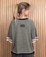 Buzo de punto negro con diseño holgado, mangas codo y detalles en tono tostado y blanco en el cuello redondo, puños y ruedo.