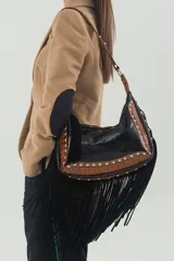 Cartera de cuero vacuno negro con detalles en cuero grabado croco color whisky, flecos largos, tachas metálicas y correa ancha corta forrada en cuero. Incluye correa larga desmontable y regulable.