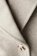 Abrigo cruzado de lana hasta la rodilla, con solapas de muesca, cierre de doble botonadura frontal y bolsillos insertados. Presenta trabillas con botón en los puños y abertura posterior, completamente forrado.