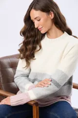 Buzo de tejido de punto con diseño de rayas horizontales en tonos blanco, gris y rosado. Presenta cuello redondo, mangas largas y terminaciones acanaladas en puños y ruedo. Incluye un pequeño aplique de cuero sintético en la parte inferior.