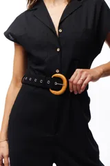 Mono negro con cuello camisero, mangas cortas, cinturón con hebilla circular de bambú y bolsillos laterales.