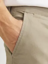 Pantalón chino slim de tiro medio color beige, con cierre de cremallera y bolsillos laterales.