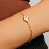 Pulsera dorada con cadena de eslabones y dije con el signo zodiacal Leo en color blanco.