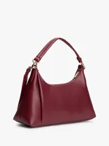 Cartera tipo hobo de Tommy Hilfiger en color bordó, confeccionada en poliuretano con acabado liso. Cuenta con compartimento principal con cierre de cremallera, bolsillo interior con cierre, asa superior y correa ajustable y extraíble. Presenta el logo metálico de la marca en relieve en la parte delantera y detalles en herrajes dorados.