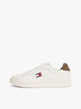 Zapatillas de estilo tenis confeccionadas en piel napa blanca, con diseño de corte bajo y cordones. Presentan un panel a contraste en el talón en color marrón y el parche distintivo de Tommy Jeans en el lateral.