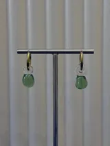 Aros tipo argolla dorada con dije colgante de vidrio soplado en forma de lágrima color verde.