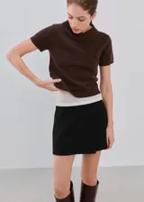 Minifalda negra de tiro medio, con diseño cruzado tipo envolvente (wrap) en el frente.