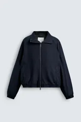 Cazadora de corte cropped confeccionada en tejido de algodón con ligero acolchado interior. Presenta cuello subido, cierre frontal con cremallera, mangas largas con puños elásticos y bolsillos laterales de vivo.