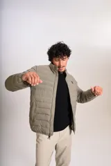 Campera puffer color beige con cierre frontal, cuello alto y logo de la marca bordado en el pecho.