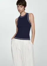 Top de punto fino sin mangas, con cuello redondo y diseño entallado. Presenta un color azul marino con detalles de ribetes en contraste en color blanco en el cuello, sisas y ruedo.