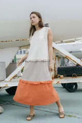 Vestido maxi sin mangas de corte relajado y diseño escalonado en bloques de color blanco, beige y naranja, con detalles de microvolados en los hombros y cortes de la falda.