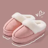 Pantuflas de gamuza negra con plataforma, forradas internamente con corderito sintético color crema. Presentan un diseño sin talón y detalle bordado en el empeine.