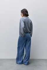 Jeans wide leg de tiro alto y pierna amplia, en lavado clásico, con bolsillos delanteros y traseros, cierre frontal con botón y presillas para cinturón.