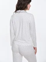 Camisa de pijama de manga larga con cuello solapa y cierre frontal de botones. Presenta un estampado sutil de pequeños corazones sobre una base de color gris melange, con detalles de ribete en contraste en el cuello y la botonera.